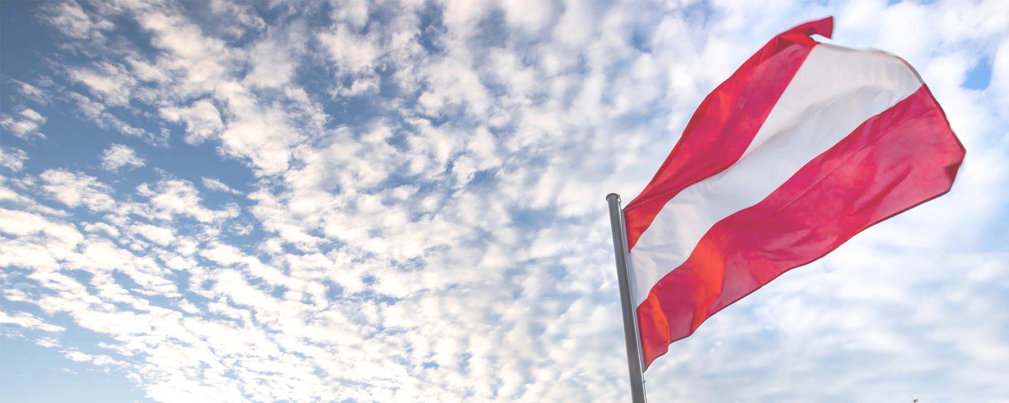 Foto: Österreichische Fahne mit wolkigem Himmel
