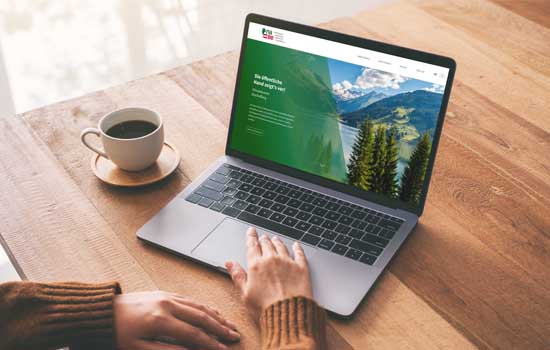 Foto: Tisch mit Laptop auf den Hände und naBe-Webseite zu sehen sind. Eine Tasse Kaffee steht daneben.