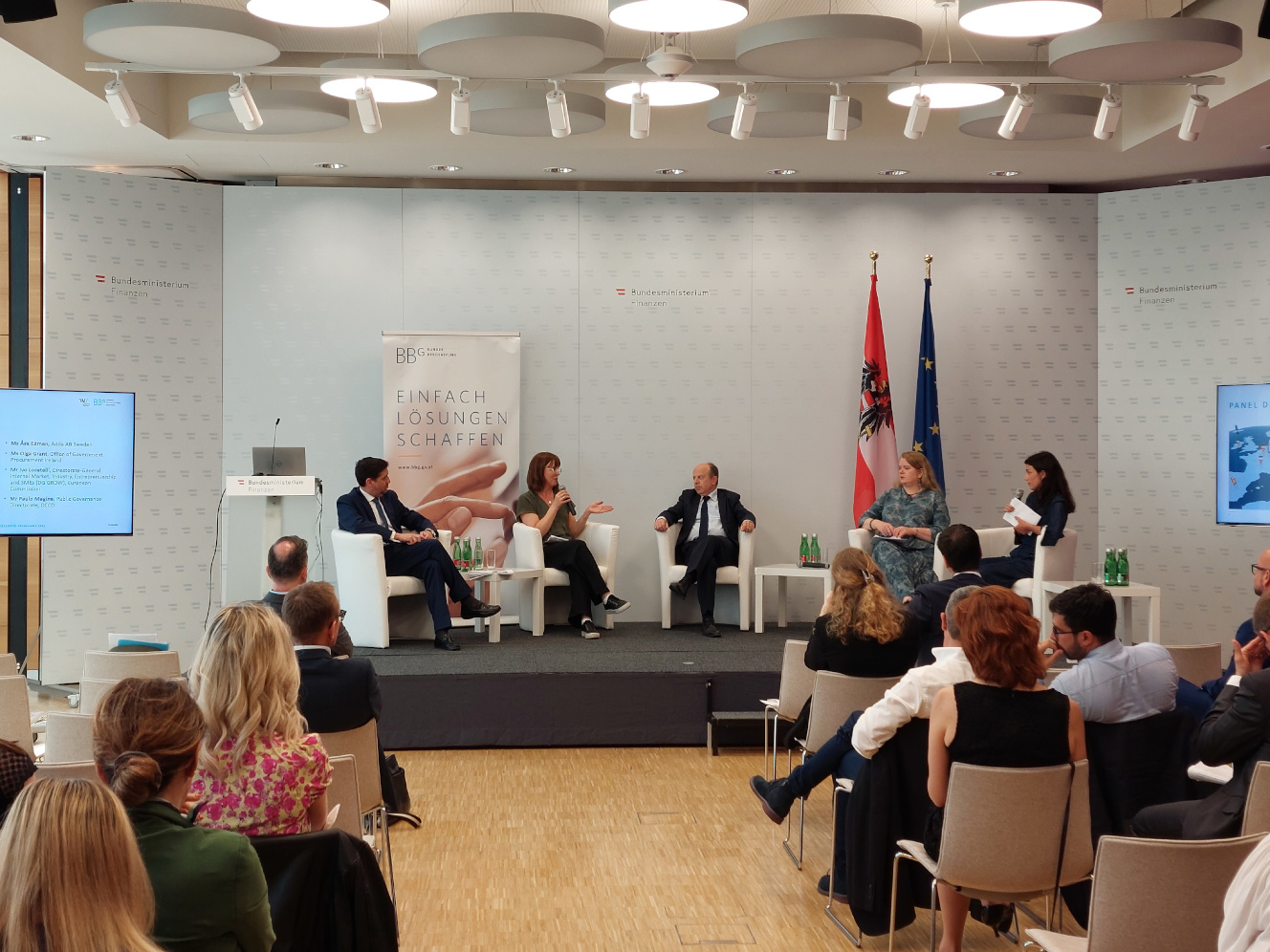 Zuhörer sitzen bei einer Podiumsdiskussion mit vier Diskutanten