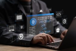Person schreibt auf einem Laptop und im Vordergrund ein digitaler Bildschirm mit Symbolen