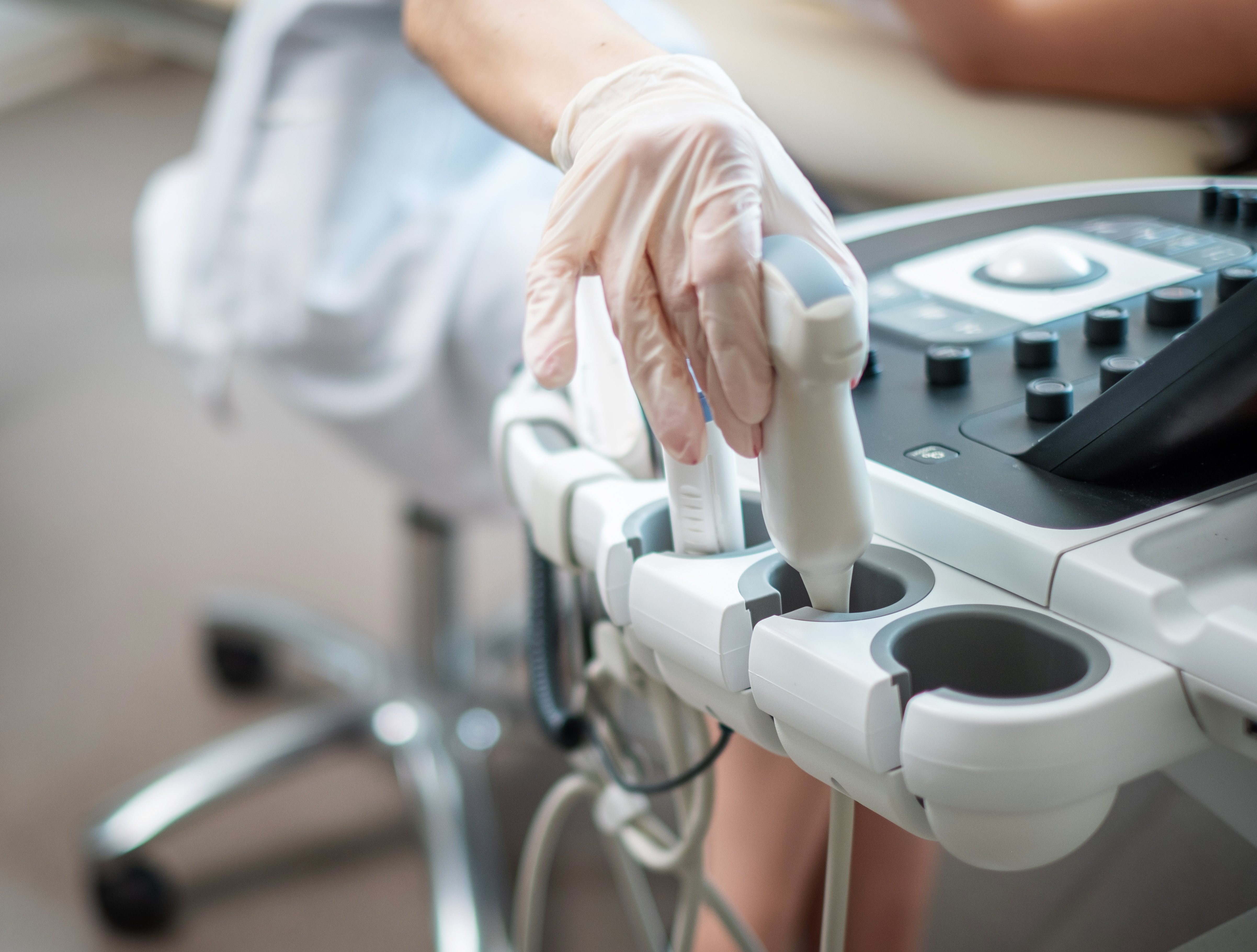 Eine Hand hält ein Ultraschallgerät und gibt es gerade in die Halterung dafür
