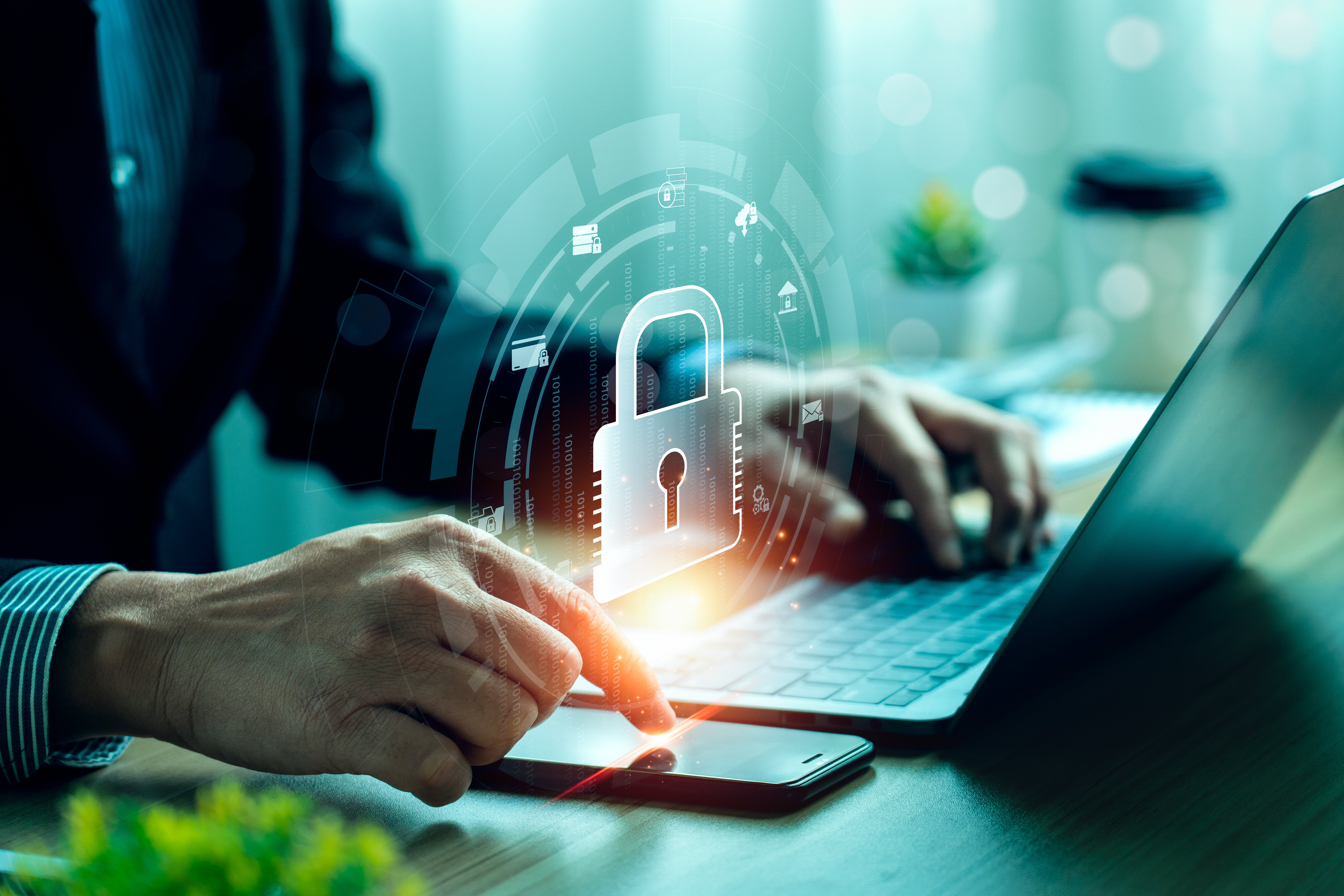 Laptop_Software_AdobeStock_662548636 Person sitzt vor Laptop und scrollt am Handy