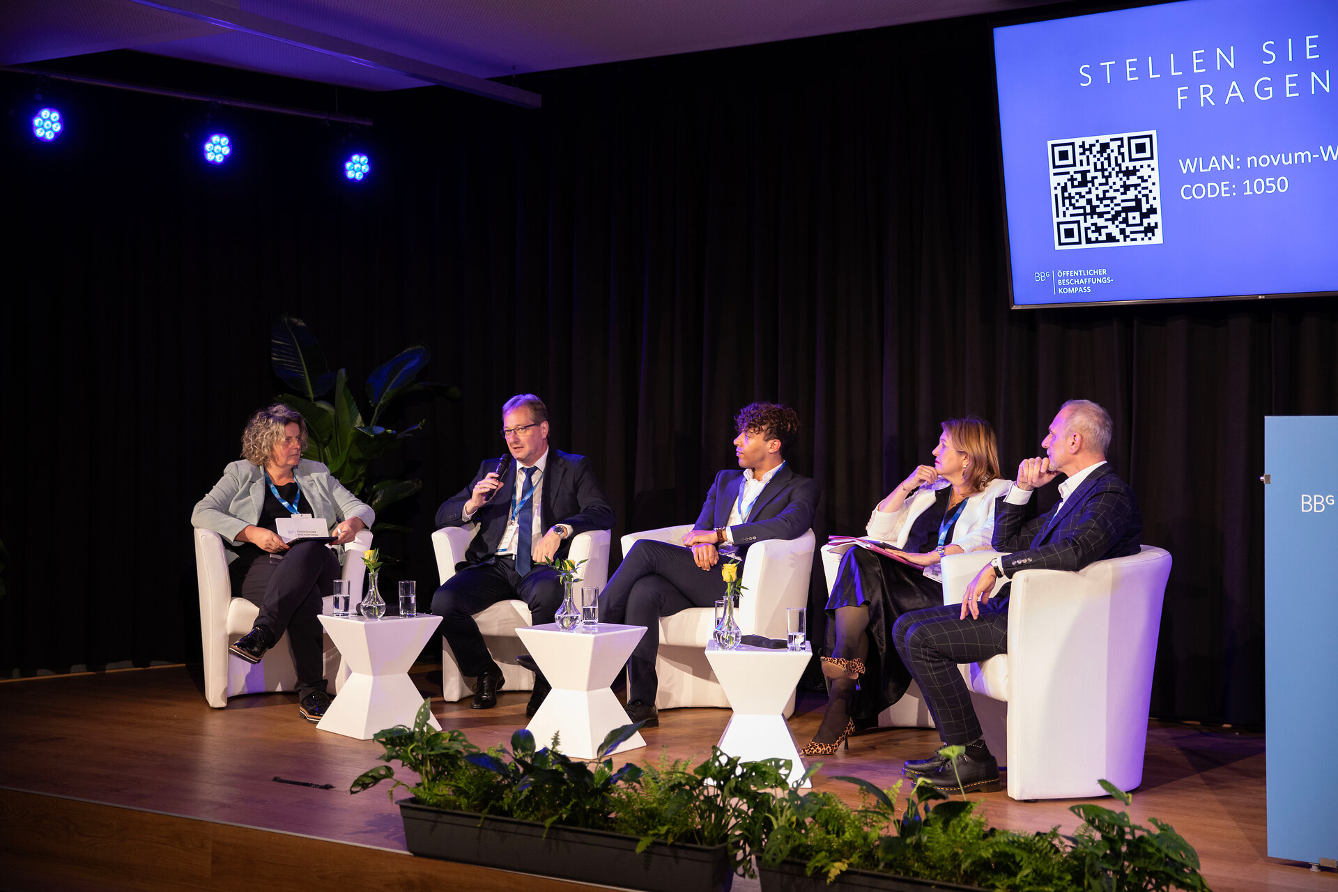 Die Moderatorin und einige Speaker bei der Podiumsdiskussion auf der Bühne