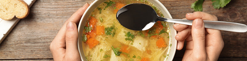 Suppe_800x200 Mensch isst eine Suppe mit Gemüse und Nudeln