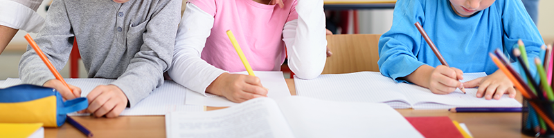 Lehrmittel_800x200 Schüler sitzen an einem Tisch über Aufgaben und Lehrmitteln