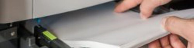 Person gibt neues Papier in den Drucker