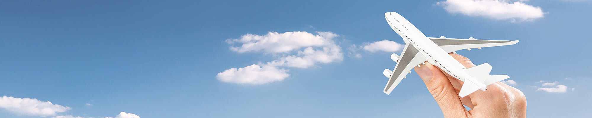 Foto: Himmel mit Wolken. Eine Hand steuert ein Flugzeug