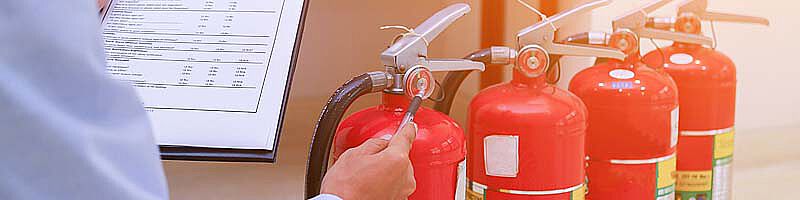 Mensch überprüft mehrere Feuerlöscher