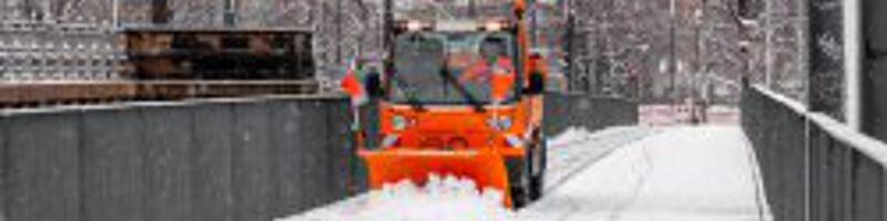 Schneeschieber schiebt Schnee von der Straße