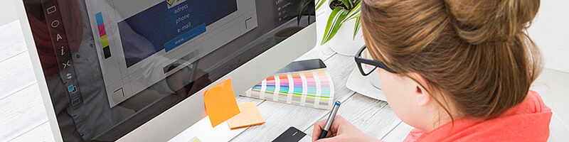 Grafikdesigner vor Monitor bei der Arbeit mit Farbmuster