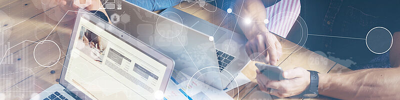 Digitalisierung AdobeStock_119946081 Auf einem Tisch sind zwei Laptops und Menschen rundherum