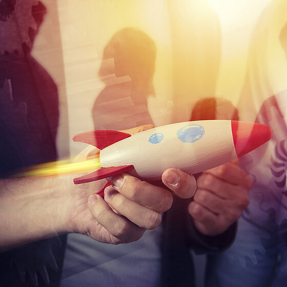 Foto: Menschen halten eine Rakete in den Händen