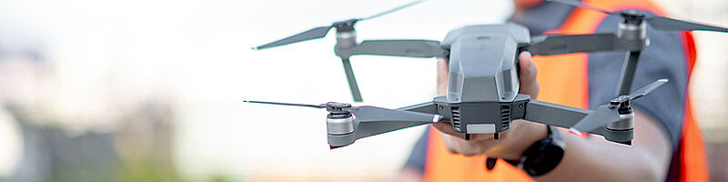 Arbeiter mit Warnweste hält Drohne in der Hand