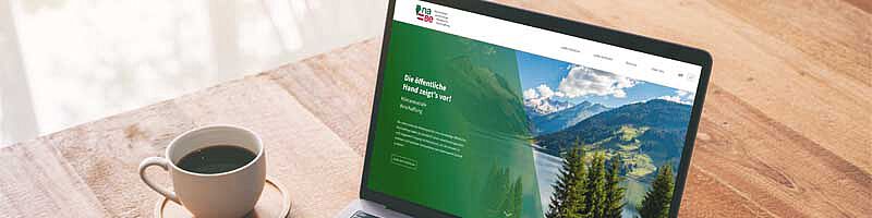 Tisch mit Laptop auf den Hände und naBe-Webseite zu sehen sind.