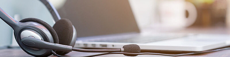 Foto: Laptop vor dem ein Headset liegt