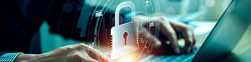 Laptop_Software_AdobeStock_662548636 Mann sitzt am Schreibtisch und tippt auf seinem Handy