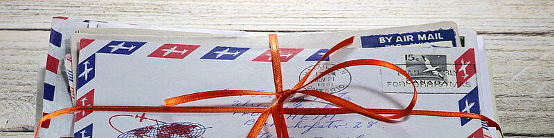 Foto: Ein Stapel internationaler Briefe, erkennbar an der Aufschrift "By AIR MAIL", mit Bändern und Schleife zusammengebunden